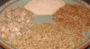 Photograph of 4 gluten sources. Top: High-gluten wheat flour. Right: European spelt. Bottom: Barley. Left: Rolled rye flakes. Image/Pdeitiker