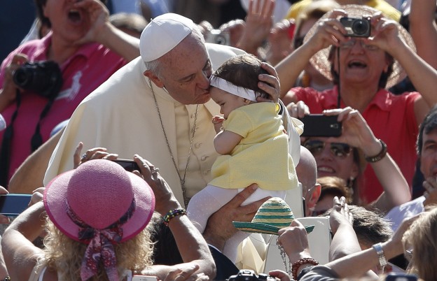 Pope Francis kisses a baby girl as he arrives to lead his general audience in St. Peter's Square at the Vatican May 13. (CNS photo/Paul Haring) See POPE-AUDIENCE May 13, 2015.